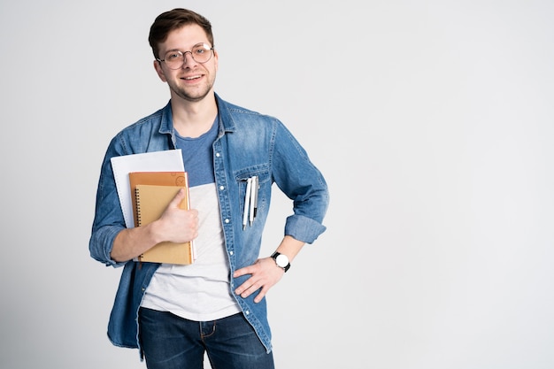 Confident student. portrait of handsome young man holding books. Isolated on white.