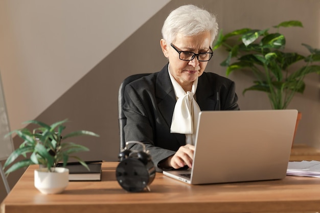 Confident stylish european middle aged senior woman using laptop at workplace stylish older mature s