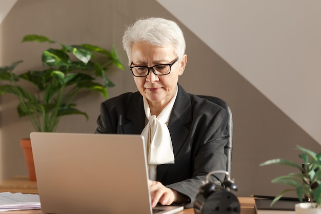 Confident stylish european middle aged senior woman using laptop at workplace stylish older mature s