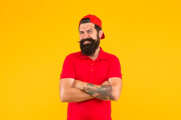 Confident and stylish. Happy hipster yellow background. Bearded man in trendy hipster style. Hipster lifestyle. Cool hipster with beard wear baseball cap. Fashion and style. Barbershop. Beard barber.