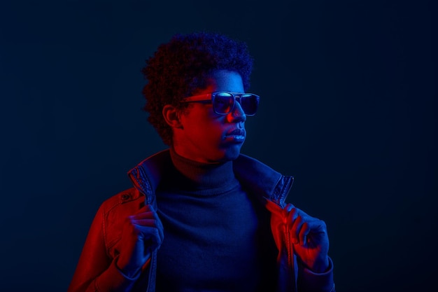 A confident stylish man model puts on leather jacket over dark background