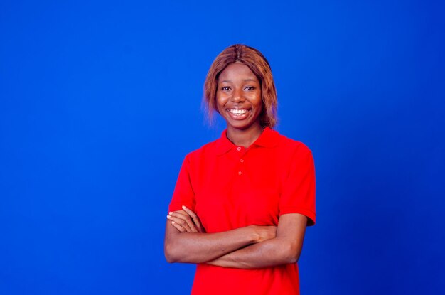 Confident woman Confident young woman keeping arms crossed and smiling while standing isolated on blue