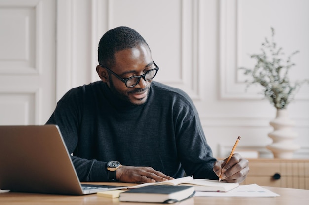 Confident young Afro american businessman working remotely online while sitting at home office