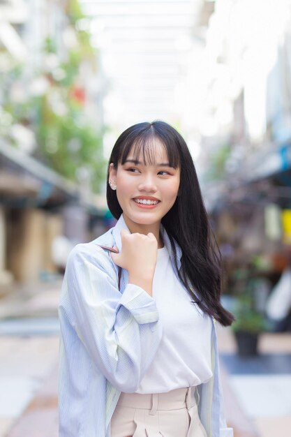 Confident young Asian female who  smiles happily as she commute to work through the old town.