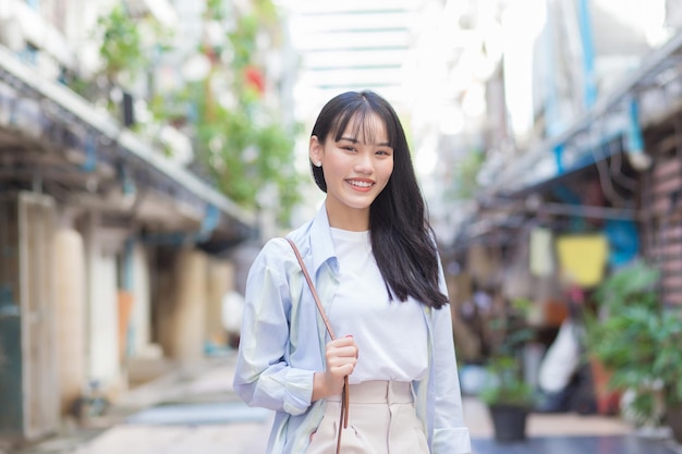 Confident young Asian woman who wears a blue white shirt smiles happily as she commute to work