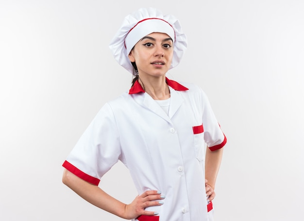 Confident young beautiful girl in chef uniform putting hands on hip 