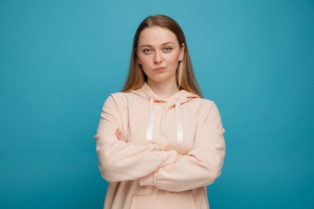 Confident young blonde woman standing with closed posture 