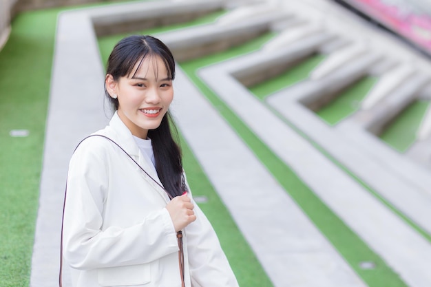 Confident young business Asian working woman who wears a white shirt and shoulder bag smiles happily