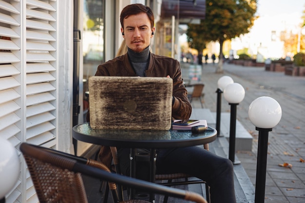 Confident young businessman having video call and online business conference via laptop in cafe