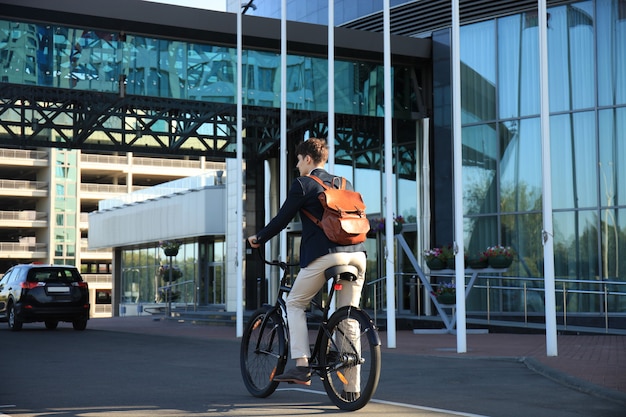 Confident young businessman walking with bicycle on the street in town.