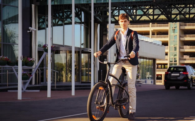 Confident young businessman walking with bicycle on the street in town