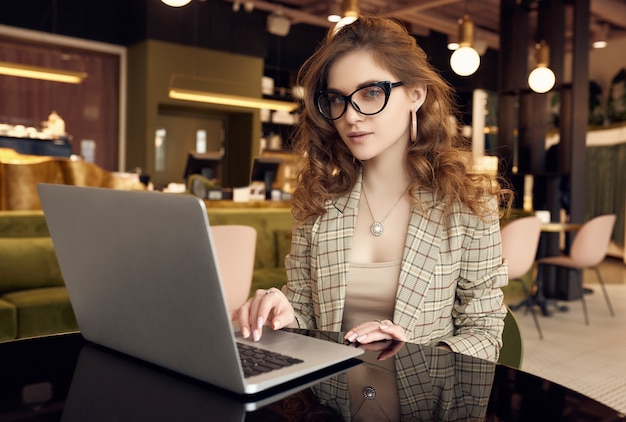 Confident young businesswoman in smart casual wear working on laptop