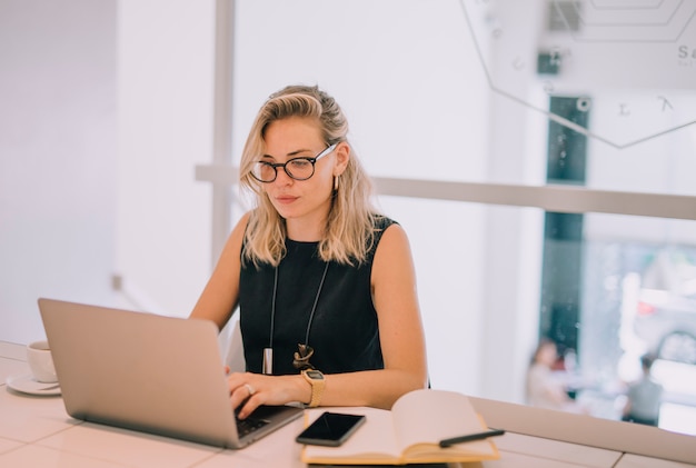 Confident young businesswoman using laptop at workplace in the office