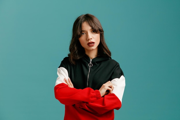 Confident young caucasian woman looking at camera while keeping arms crossed isolated on blue background