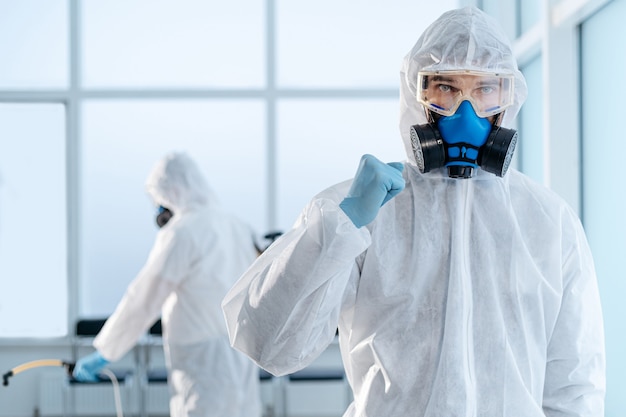 Confident young disinfector standing in an infected room