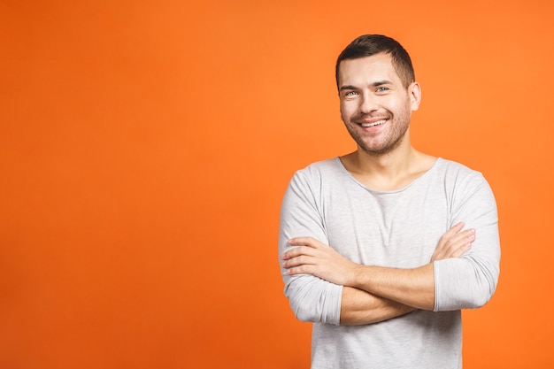 Confident young handsome man keeping arms crossed and smiling