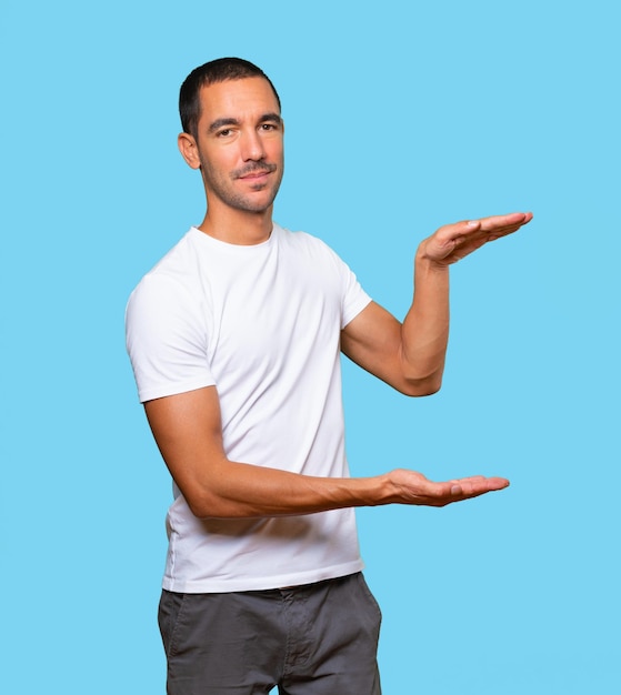 Confident young man doing a gesture of holding something with his hands