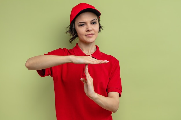 Confident young pretty delivery woman gesturing time out sign 