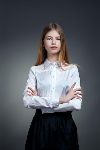 Confident young school child in uniform posing with folded arms