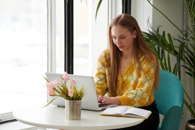 Confident young woman in smart casual wear working on laptop