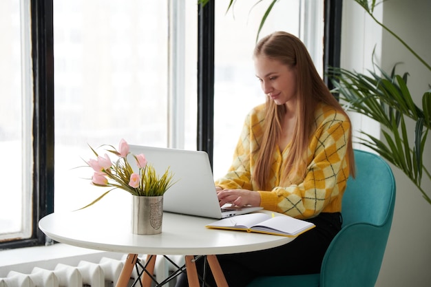 Confident young woman in smart casual wear working on laptop