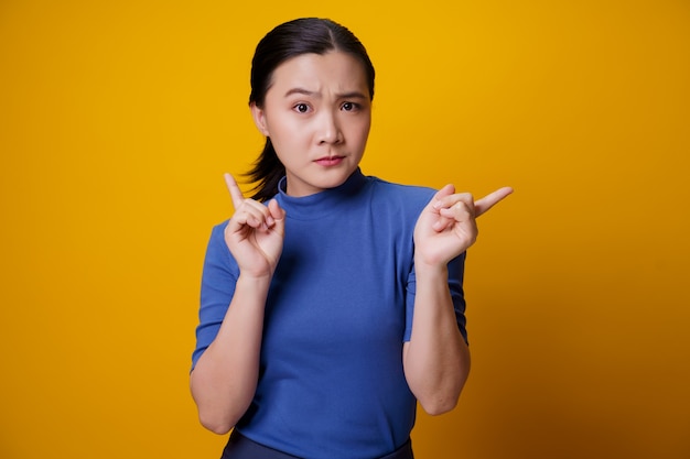 Confused Asian woman thinking and standing on yellow.