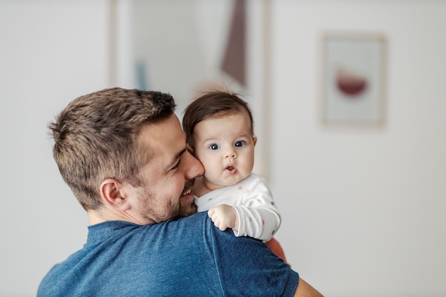 A confused baby in father39s arms looking at the camera and making faces