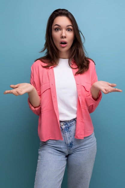 Confused brunette woman with hair below her shoulders in a shirt shrugs her shoulders