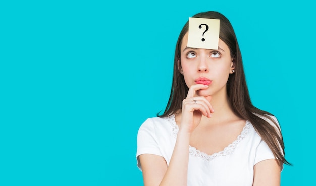 Confused female thinking with question mark on sticky note on forehead.