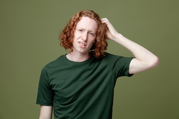 Confused putting hand on head young handsome guy wearing green t shirt isolated on green background