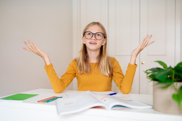 Photo confused teen girl studying with books at home and raising her hands