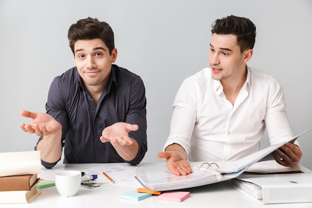 Confused two young business men colleagues