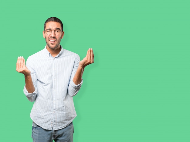 Confused young man making an italian gesture of not understand