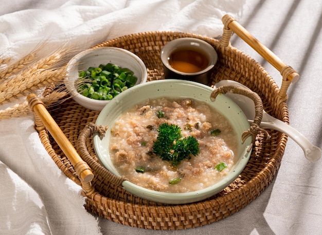 Congee minced beef congee with spring onion in a dish side view on grey background