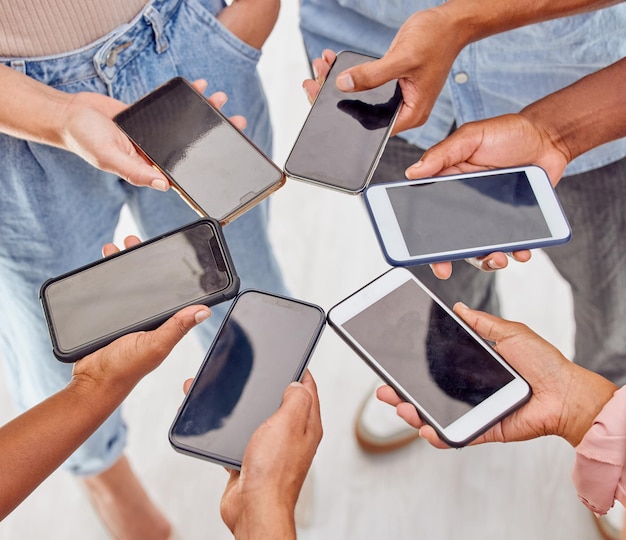 Connected as a group Shot of a group of unrecognizable people standing in a circle and using digital devices in an office