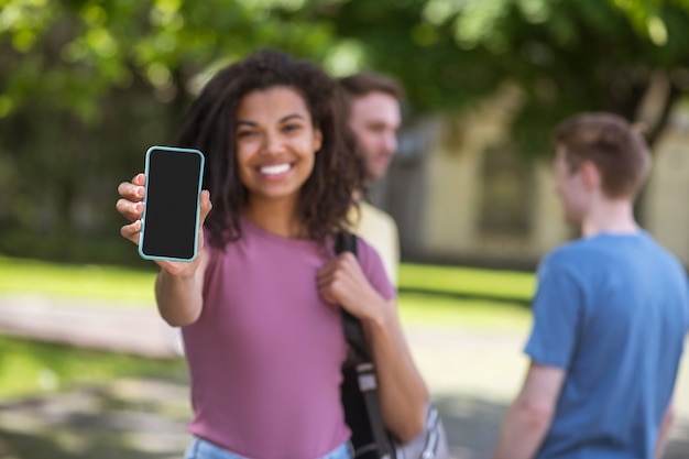 Connected. Cute mulatta with a smartphone smiling nicely