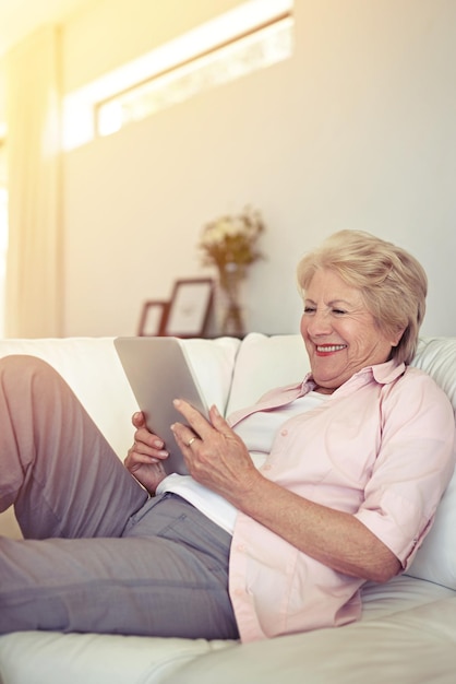 Connected from the comfort of the couch Shot of a senior woman using her digital tablet at home