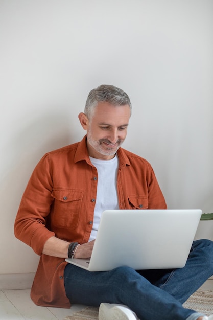 Connected. Good-looking gray-haired man working on laptop