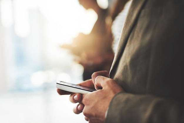 Connecting with multiple likeminded individuals Shot of a businessperson using his cellphone with colleagues blurred in the background