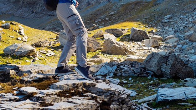 To conquer the mountains a young man travels in the mountains walking on rocks legs closeup