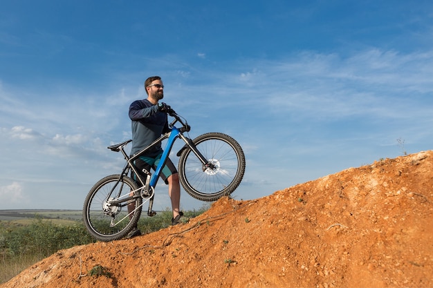 Conquering mountain peaks by cyclist in shorts and jersey on a modern carbon hardtail bike