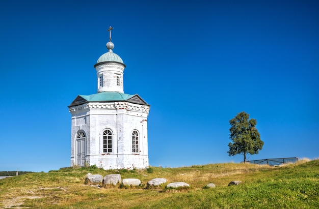 Constantine-Eleninskaya chapel near the walls of the Solovetsky monastery and a tree against the blue sky