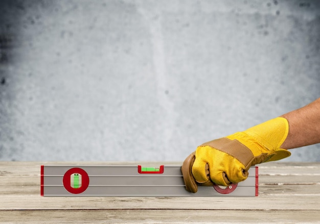 Construction Carpenter Hand in Glove Holding Level on White