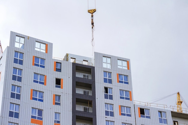 Construction crane and house under construction against the background of a rainy sky