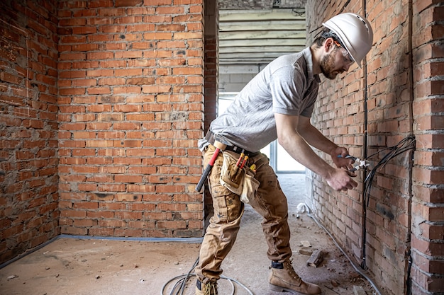 A construction electrician cuts a voltage cable during a repair.