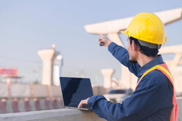 Construction Engineer using computer inspection on site highway road construction Construction worker using laptop