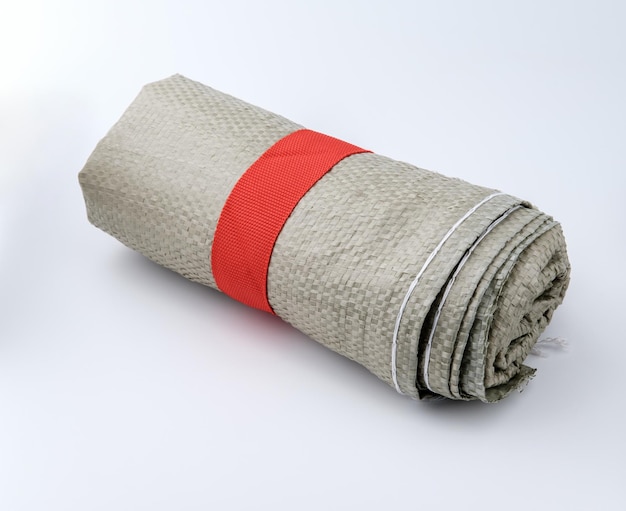 Construction garbage bags are tied in a roll with red dense tape and lie isolated on a gray background.