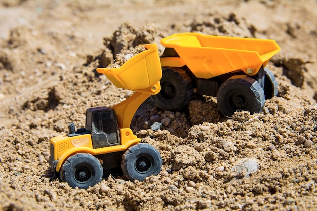 Construction machinery toys on the sand in sunny day Yellow and black colors toy building toys