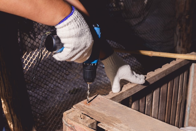 Construction man workers in blue shirt with Protective gloves and working with power drill