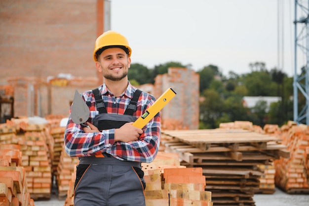 Construction mason worker bricklayer installing red brick with trowel putty knife outdoors